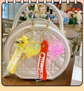 Glow-in-the-dark lollipop keychain with sequins on a quilted handbag for gift decor