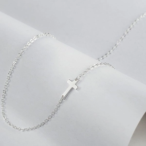 Detailed view of a sleek silver cross pendant on a minimalist double layered chain necklace