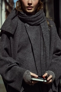 Detail of dark grey knit cardigan featuring an integrated matching wool-like scarf