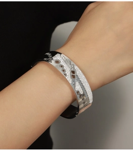 Detailed close-up of wide silver bangle featuring hollow floral patterns and sparkling crystals