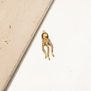 Macro detail of a gold octopus pendant with pink gem eyes and crystal tentacles