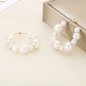 Close-up of gold stainless steel U-shaped earrings with alternating white pearls