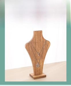 Detail of wooden necklace bust stand with step base displaying silver jewelry chains