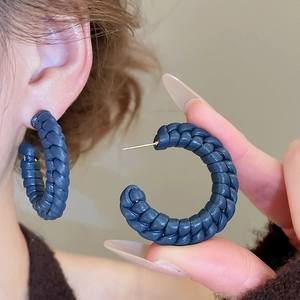 Detail showing deep blue woven leather texture on C-shaped hoop earring with golden stud
