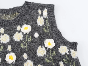 Dettaglio del gilet in maglia grigio scuro con applicazioni di margherite 3D in rilievo