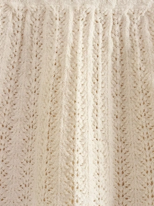 Vista macro dettagliata del tessuto a maglia bianco con motivi all'uncinetto traforati