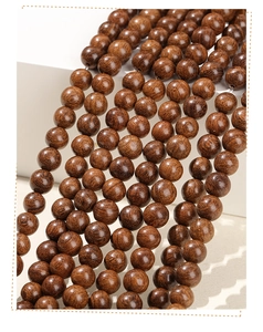 Macro shot of polished round sandalwood beads with natural deep reddish-brown wood grain