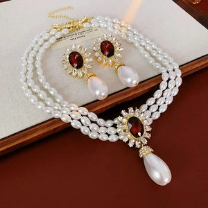 Detailed macro of vintage pearl necklace and earrings set with red gemstone pendants