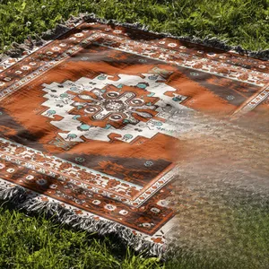 Detail of bohemian outdoor camping blanket with orange geometric patterns and woven tassels