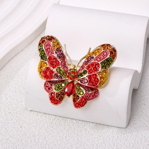 Elegant gold butterfly brooch with colorful rhinestones on a white display pedestal
