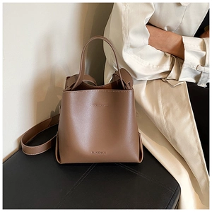 Close-up of brown leather bucket bag showing premium texture and long shoulder strap