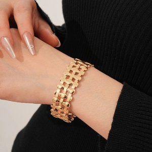 Macro shot of gold oval triple-layer woven open bangle showing polished metal texture