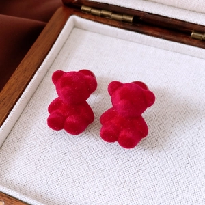Detail view of red flocked bear stud earring in a wooden jewelry box with a soft liner