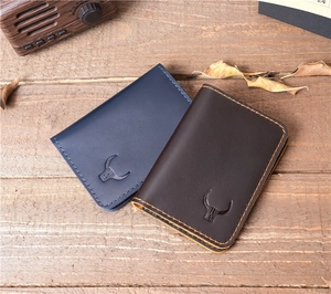 Close-up of blue and brown leather card holders with bull logo on a wooden surface