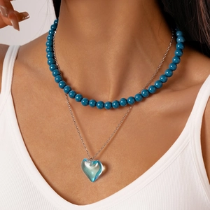 Close-up of double-layer beaded necklace with blue heart pendant and round glass beads