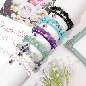 Natural stone bead bracelets with Evil Eye charms in multiple colors on a display stand