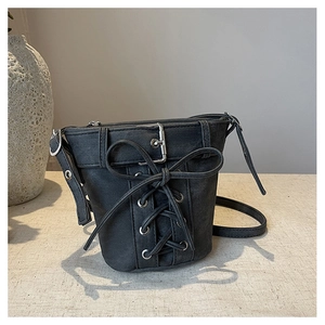 Détail du sac seau en denim noir avec nœud en ruban et garnitures en métal argenté