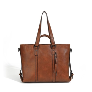 Detail of soft brown PU leather tote with side zipper and metallic hardware rings