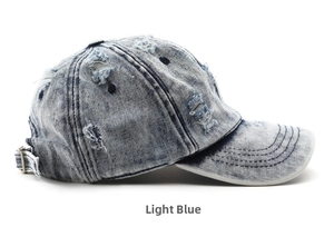 Dettaglio del cappello in denim azzurro con fori consumati e fibbia in metallo regolabile