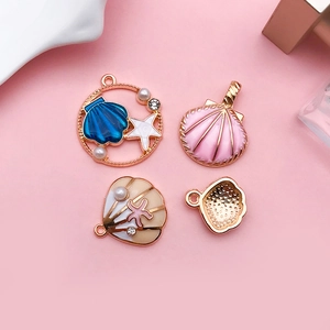 Flat lay of colorful enamel shell pendants with pearls and rhinestones for DIY jewelry