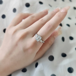 Detail of a 2-carat emerald-cut moissanite ring with baguette side stones on a finger