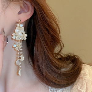 Close-up of elegant flower tassel earrings with pearls and gold plating on a model