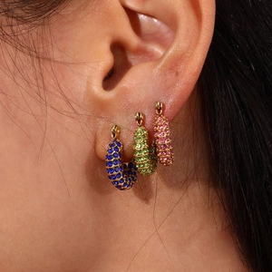 Close-up of golden hoop earrings featuring blue green and pink zircon pave settings