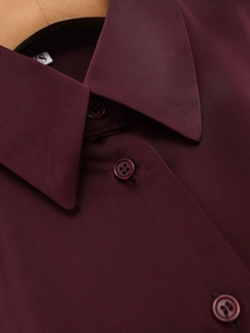 Detail of burgundy satin shirt collar and matching resin buttons on a wooden hanger
