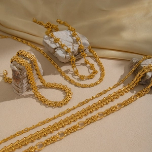 Detail of chunky gold chain necklaces on silk fabric and stone for a luxury look