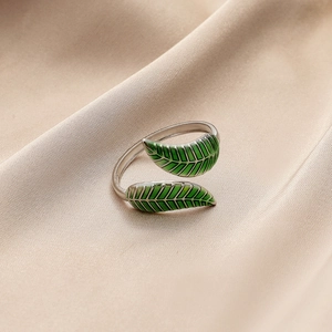 Silver adjustable leaf ring with green enamel leaves on elegant champagne silk fabric