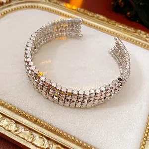 Layered silver open bangle with minimalist beaded design on a luxury white cushion