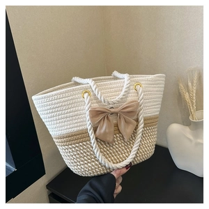 Détail du sac cabas tissé avec un nœud beige et des poignées en corde de coton