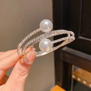 Macro shot of silver layered wrap bracelet with pavé rhinestones and two large pearls