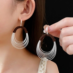 Silver multi-layered hoop earrings with brown woven fabric detail on a model