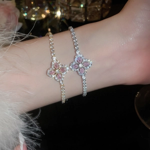 Gros plan de bracelets trèfles roses sertis de pierres brillantes sur fond sombre