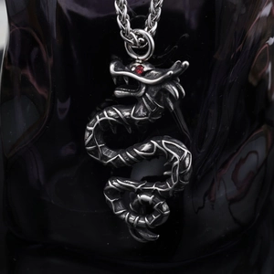 Close-up of vintage steel dragon pendant with red zircon eye on a metal chain necklace