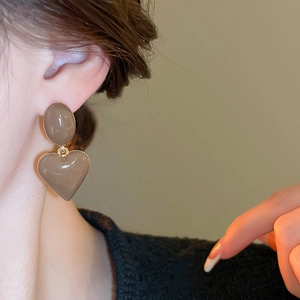 Close-up of elegant mocha heart drop earrings worn by model with minimalist styling