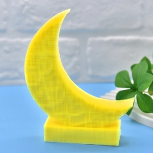 Gelbe 3D-Druck Mond und Sterne Skulptur mit Sockel auf hellblauem Tisch