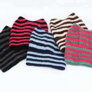 Flach liegende gestreifte Strickmützen mit Katzenohren in verschiedenen bunten Farben