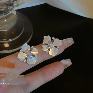 Detail of flower stud earrings featuring white shell petals and sparkling zircon accents
