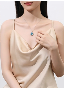 Elegant teardrop pendant necklace with a blue gemstone on a champagne silk top
