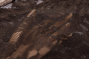 Détail du tissu en dentelle florale marron montrant la texture transparente et la maille