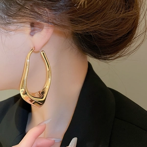 Close-up of a stylish irregular geometric gold earring worn by a model in a fashion shot