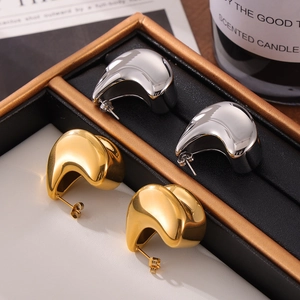 Dual-layer teardrop stud earrings in gold and silver finish on a display tray