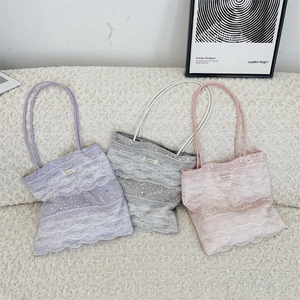 Sacs cabas à paillettes et dentelle en violet gris et rose sur un canapé blanc chic