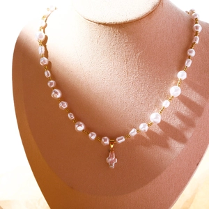 Détail d'un collier en perles baroques avec pendentif croix sur un support à bijoux élégant
