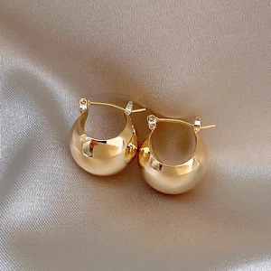 Glossy golden chunky hoop earrings on champagne silk fabric with minimalist design