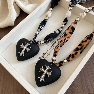 Close-up of leopard print ribbon necklace with black heart and gothic cross pendant
