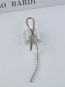 Macro shot of silver metal ear cuff featuring a knot design and long hanging chain detail