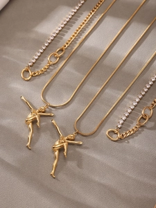 Close-up of golden ballet dancer pendant necklace with crystal accents and layered chain